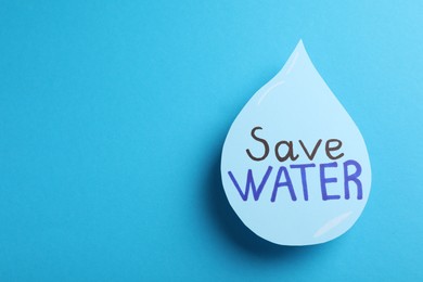 Drop with words Save Water on light blue background, top view. Space for text