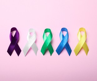 Colorful ribbons on pink background, flat lay. World Cancer Day