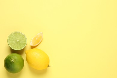 Fresh ripe lemons and limes on yellow background, flat lay. Space for text