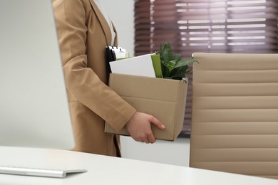 Upset dismissed woman carrying box with personal stuff in office, closeup