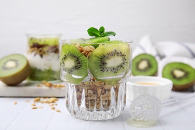 Photo of Delicious dessert with kiwi and muesli on white table, closeup