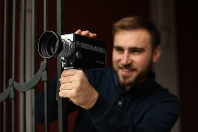 Young man with vintage video camera outdoors, focus on lens