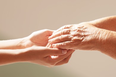 Helping hands on light background, closeup. Elderly care concept