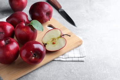 Fresh ripe red apples and knife on light grey table, space for text