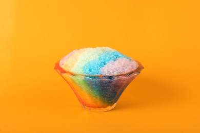 Rainbow shaving ice in glass dessert bowl on orange background