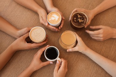 Photo of Friends drinking coffee at wooden table in cafe, top view