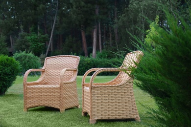 Garden rattan armchairs on green grass at backyard