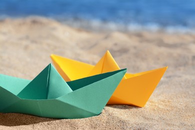 Two paper boats near sea on sunny day, closeup