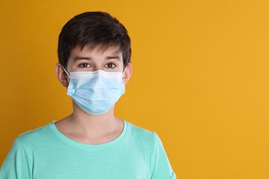 Boy wearing protective mask on yellow background, space for text. Child safety