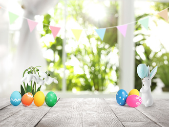 Bright Easter eggs, flowers and bunny figure on table indoors