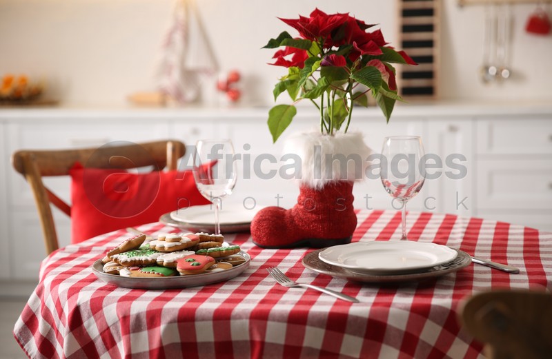 Festive table setting with Christmas cookies and Poinsettia in kitchen