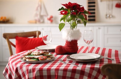 Festive table setting with Christmas cookies and Poinsettia in kitchen
