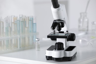 Photo of Modern medical microscope on white table in laboratory, space for text