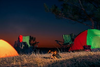 Camping tents and chairs in wilderness at night