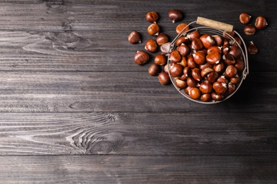 Fresh sweet edible chestnuts on black wooden  table, flat lay. Space for text