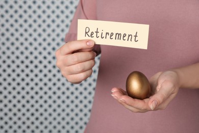 Woman holding golden egg and card with word retirement on light background, closeup. Pension concept