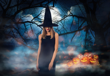 Witch with spooky Jack O Lantern pumpkins and misty forest under full moon on Halloween