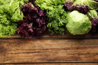 Photo of Different sorts of lettuce on wooden table, flat lay. Space for text