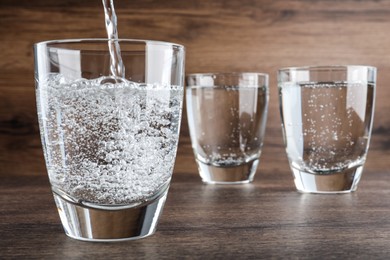 Pouring soda water into glass on wooden table