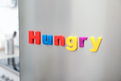 Word HUNGRY of magnetic letters on refrigerator door indoors