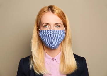 Woman wearing handmade cloth mask on beige background. Personal protective equipment during COVID-19 pandemic