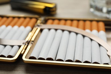 Open case with tobacco filter cigarettes on wooden table, closeup