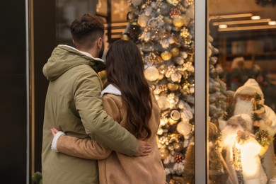 Lovely couple near store decorated for Christmas outdoors, back view