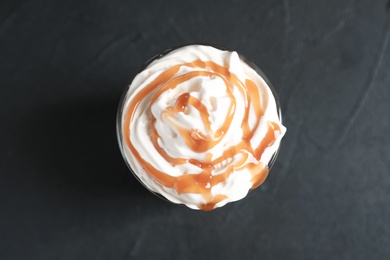 Glass with delicious caramel frappe on grey background, top view
