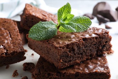 Photo of Delicious chocolate brownies with fresh mint on marble board, closeup