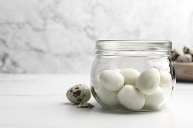 Photo of Unpeeled and peeled boiled quail eggs on white table, space for text