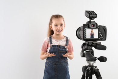 Cute little blogger recording video on white background