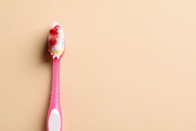 Photo of Toothbrush with blood on beige background, top view and space for text. Gum inflammation