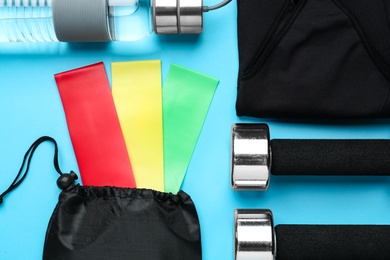 Flat lay composition with fitness elastic bands and sport accessories on light blue background