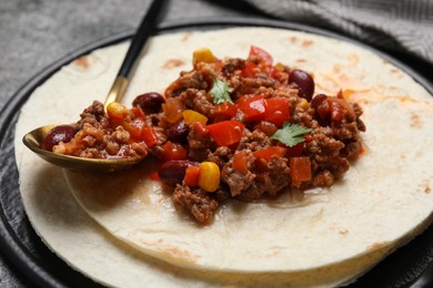 Tasty chili con carne with tortilla on grey table, closeup