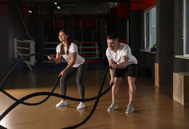 Couple working out with battle ropes in gym