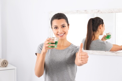 Young woman with mouthwash in bathroom. Teeth and oral care