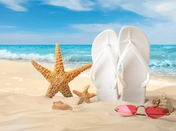 White flip flops, starfishes, sea shells and sunglasses on sandy beach