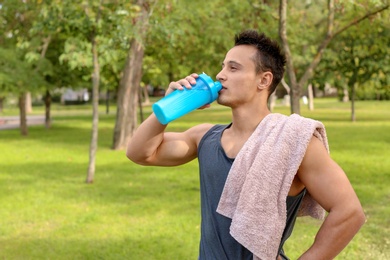 Young man drinking protein shake in park