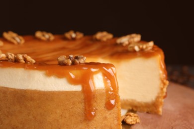 Photo of Sliced delicious cheesecake with caramel and walnuts on board, closeup
