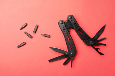 Compact portable black multitool and details on red background, flat lay