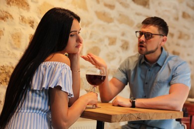 Young woman getting bored during date with man at cafe
