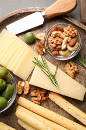 Snack set with delicious Parmesan cheese on wooden plate, top view