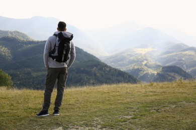 Man with backpack in mountains, space for text. Tourism equipment