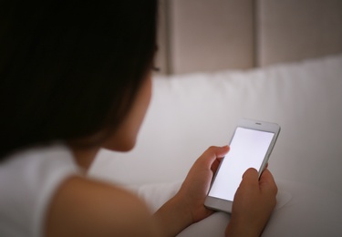 Young woman with nomophobia using smartphone in bed. Insomnia concept