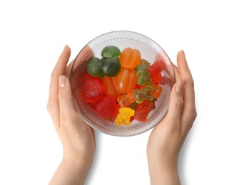 Woman holding bowl with delicious gummy candies on white background, top view