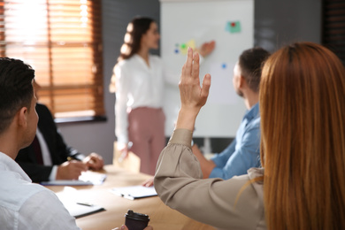 Woman raising hand to ask question at seminar in office, closeup