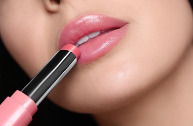 Closeup view of young woman applying beautiful nude lipstick