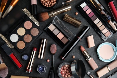 Flat lay composition with makeup products on black slate table