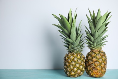 Fresh ripe juicy pineapples on light blue wooden table. Space for text
