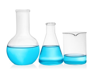 Different laboratory glassware with light blue liquid on white background